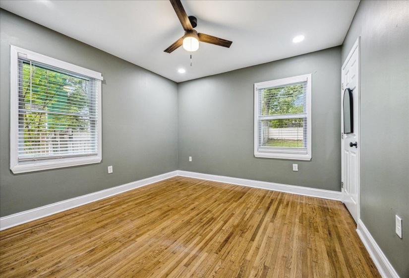Room featuring wood-finish flooring, two windows with blinds, a ceiling fan with integrated lighting, and recessed ceiling lights