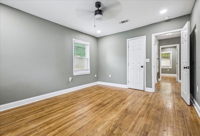 Spacious room featuring wood-finish flooring, light gray walls, white trim, and a ceiling fan with integrated lighting