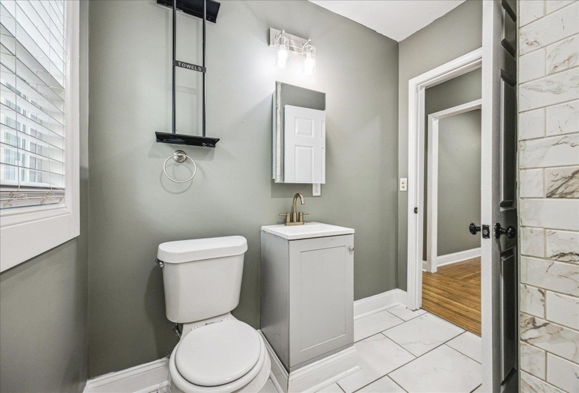 Bathroom featuring a light gray vanity with a single basin, a gold-finish faucet, and coordinating wall-mounted lighting