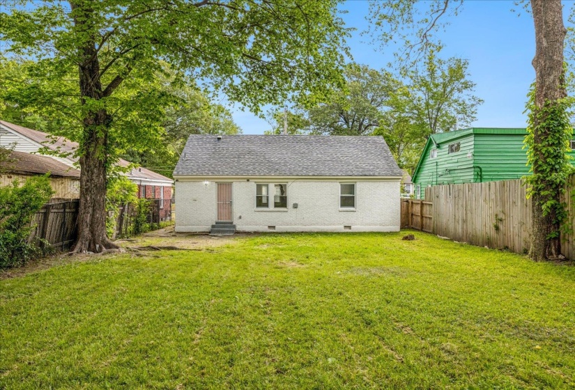 Spacious backyard featuring a manicured lawn, mature trees, and a privacy fence
