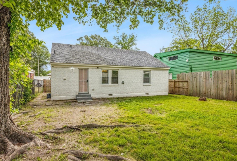 Backyard area featuring established lawn, mature tree, and a wood privacy fence