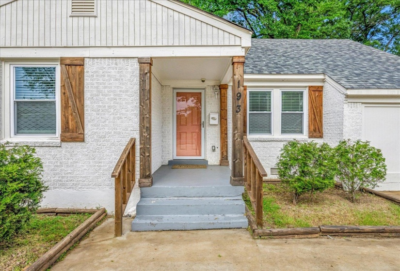 White brick exterior with natural wood shutters and a vibrant orange front door