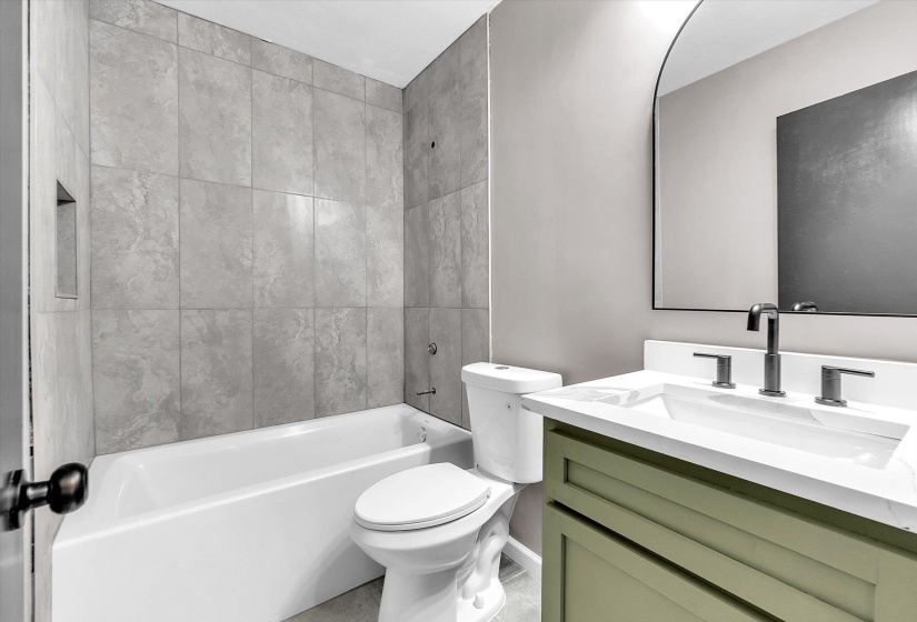 Contemporary bathroom featuring a tub-shower combination with light gray wall tiling and an integrated shower niche