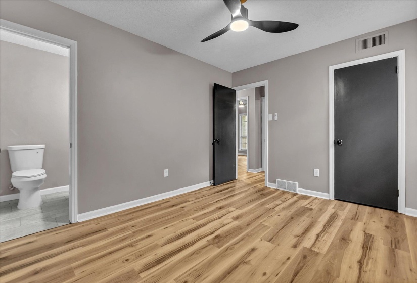 Spacious room featuring wood-finish flooring, light grey painted walls, and white trim
