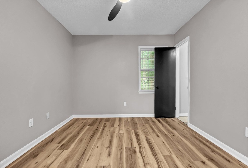 Room featuring light gray walls, wood-finish flooring, white baseboards, and a ceiling fan