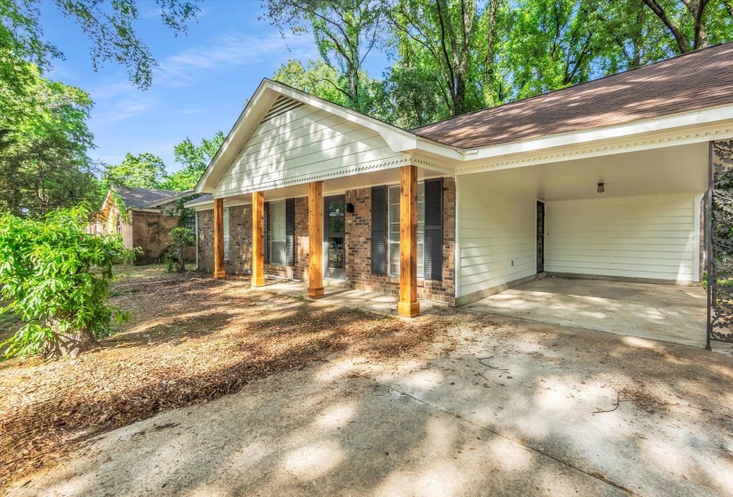 Brick and siding exterior featuring a covered carport, wood support columns, and decorative shutters