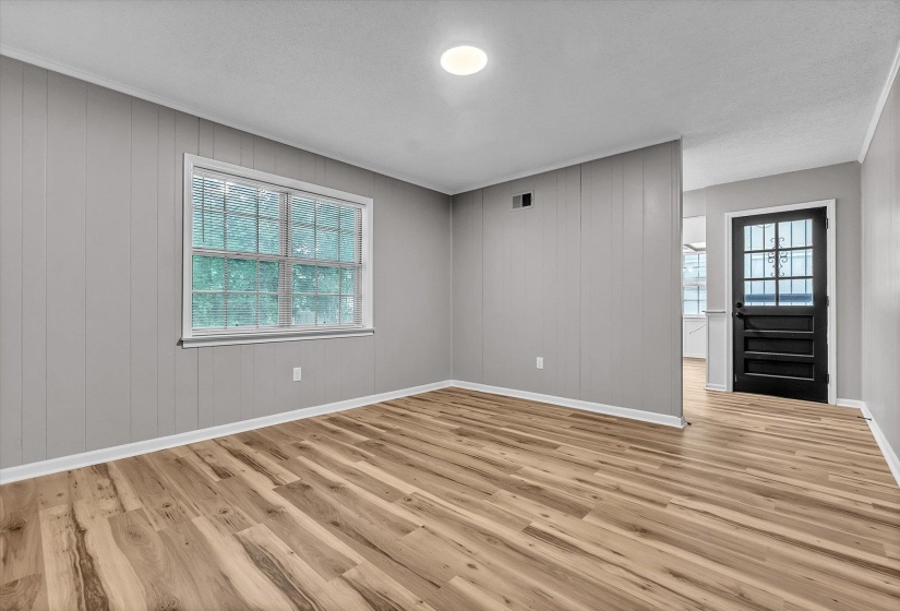 Spacious room featuring wood-finish flooring and grey paneled walls