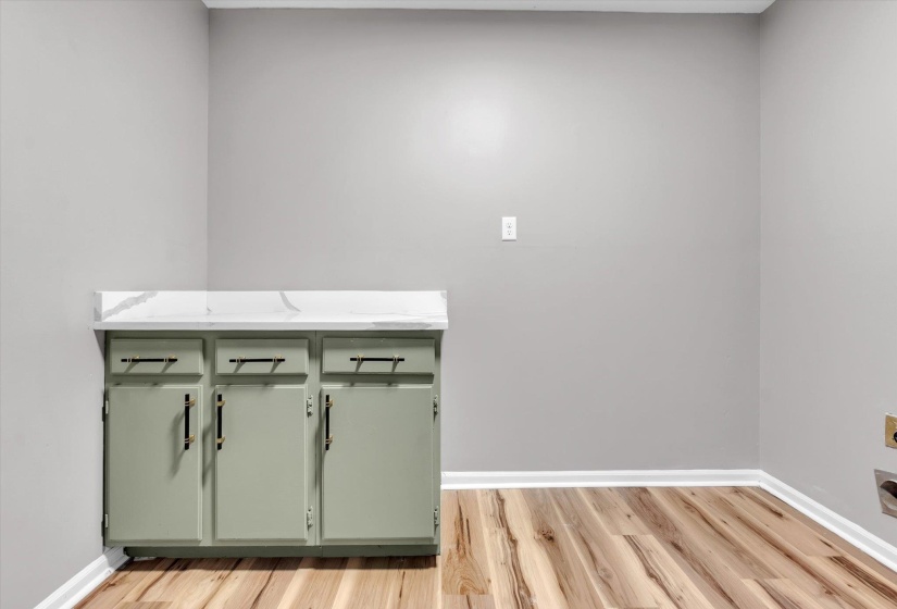 Base cabinetry with a white patterned countertop, featuring three doors and three drawers with dark hardware