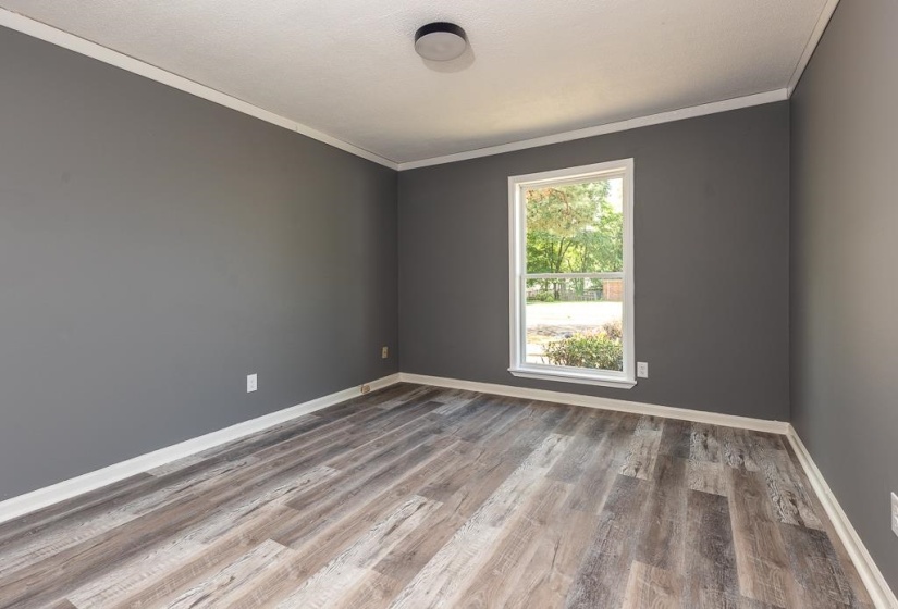 Spacious interior featuring wood-finish flooring, a single window, and a ceiling-mounted light fixture