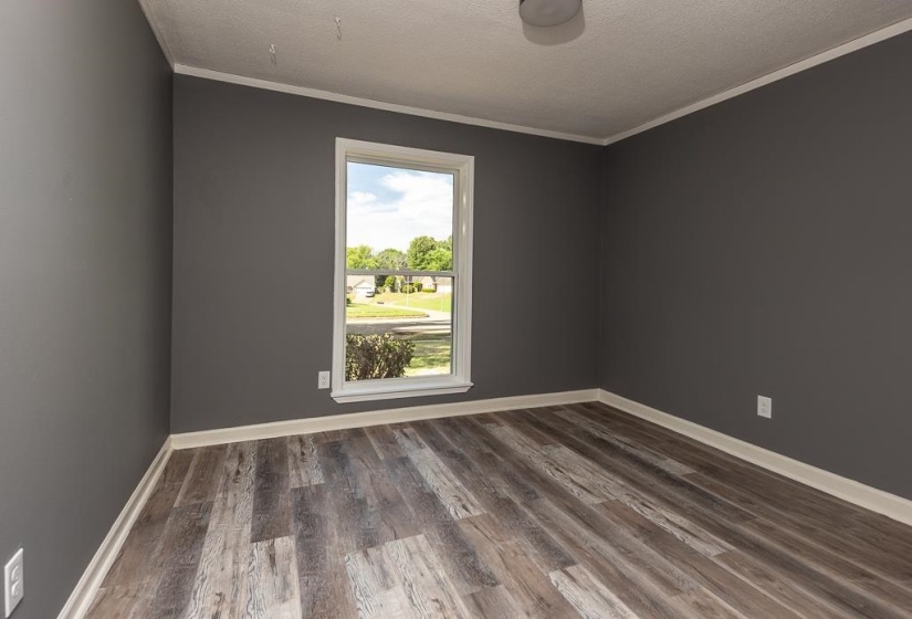Room featuring dark gray walls, wood-finish flooring, and white baseboards