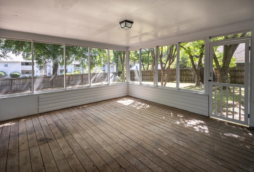 Screened-in porch featuring wood-finish flooring, a white paneled kick wall, and a full-light screen door