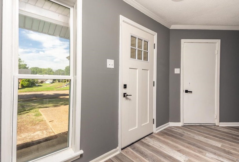 Entryway featuring a paneled door with glass inserts, matte black hardware, and wood-finish flooring