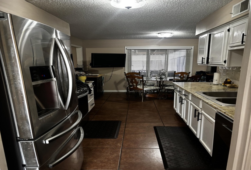 Kitchen featuring white cabinetry, stone-finish countertops, stainless steel appliances, and tile flooring