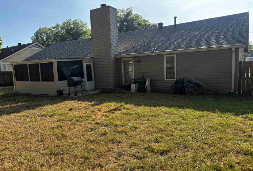 Rear exterior featuring a screened porch, prominent chimney, and a concrete patio pad