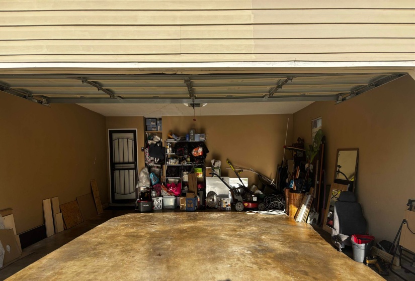 Attached garage with a concrete floor, painted interior walls, and an exterior door with a security screen