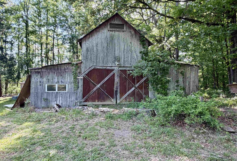 Rustic wooden barn featuring a gambrel roof and large double doors with X-bracing