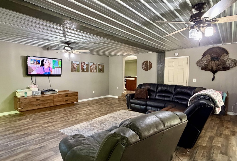 Spacious living area featuring a corrugated metal ceiling and wood-finish flooring