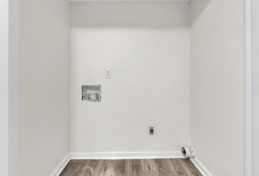 Utility area featuring wood-finish flooring, white baseboards, and a white wall finish