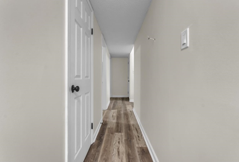Hallway featuring wood-finish flooring, white baseboards, and light neutral wall paint
