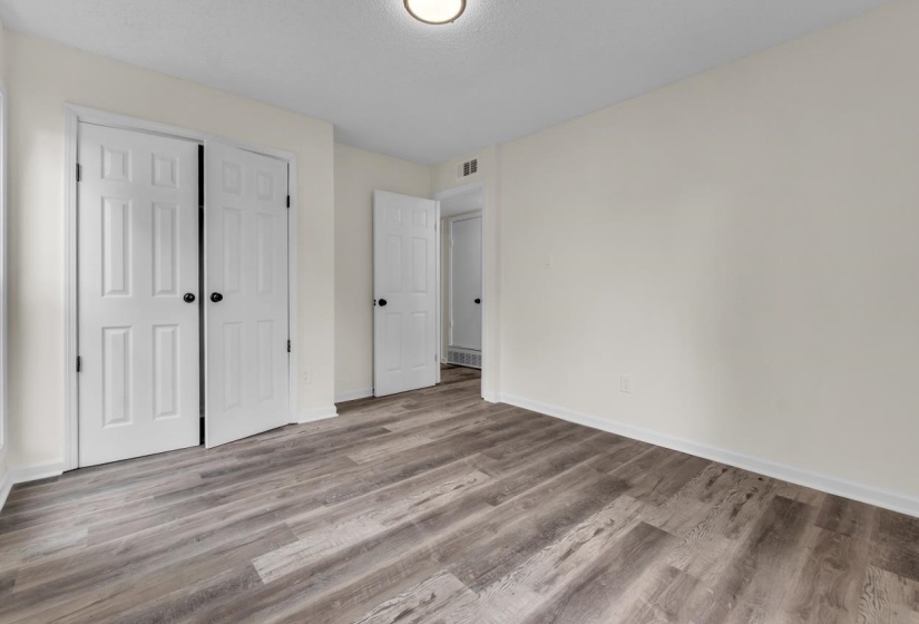 Room featuring wood-finish flooring, light-colored walls, white baseboards, and white paneled doors