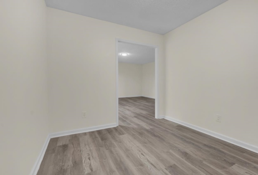 Interior room featuring wood-finish flooring, light-toned walls, and white baseboards