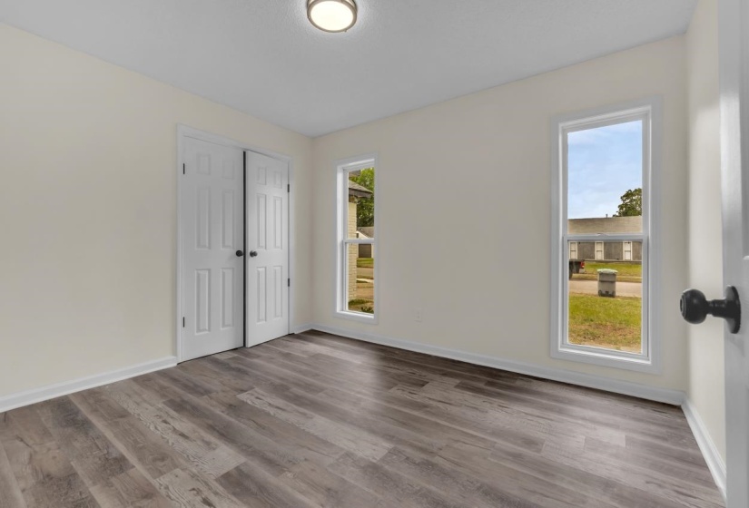 Spacious room featuring wood-finish flooring, light-toned walls, and a contemporary flush-mount ceiling light