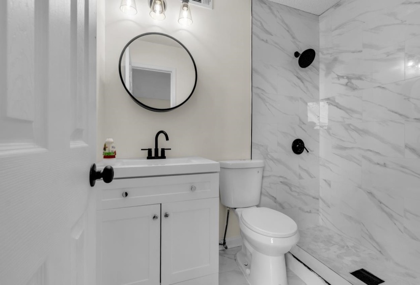 Bathroom featuring a white vanity with integrated sink, matte black faucet, and a circular wall mirror