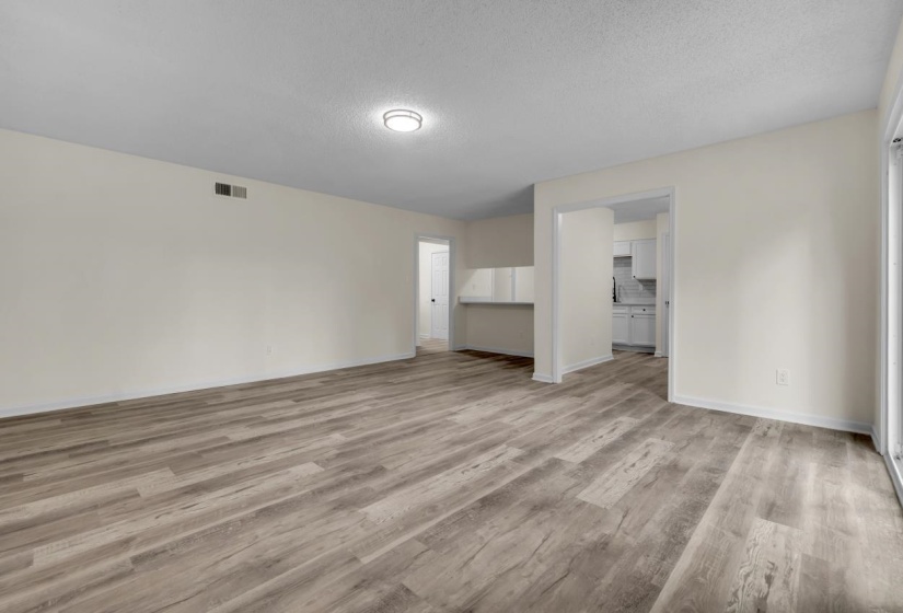 Open concept living area featuring wood-finish flooring, light neutral wall paint, and a semi-flush mount ceiling light