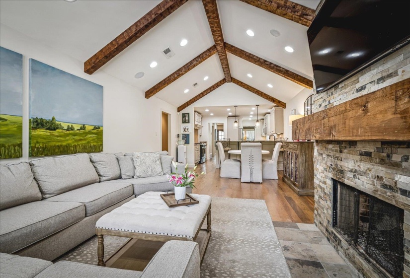 Spacious living area featuring a vaulted ceiling with exposed wood beams and recessed lighting