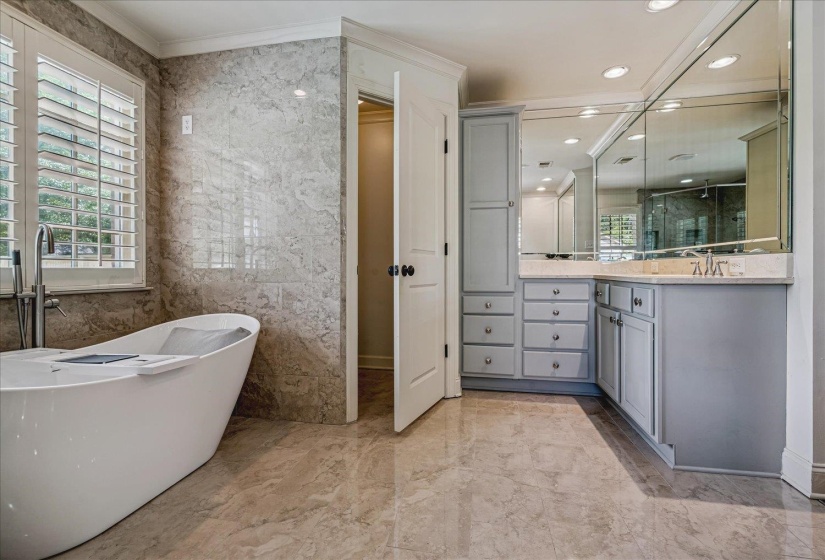 Freestanding soaking tub with floor-mounted faucet and plantation shutters