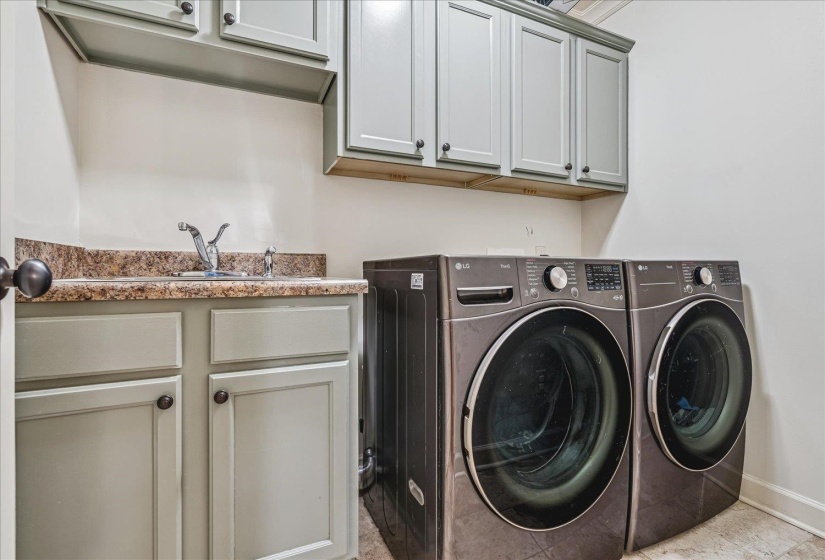 Utility room featuring a built-in sink with a countertop, upper and lower cabinetry, and contemporary flooring