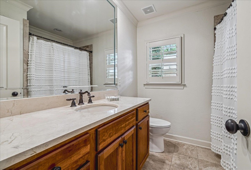 Bathroom featuring a wide vanity with an integrated sink, rich wood-finish cabinetry, and a light-toned countertop