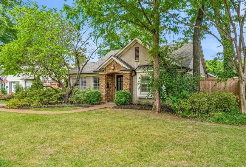 Traditional-style home featuring a stone facade entry, a gabled roofline, and well-maintained landscaping