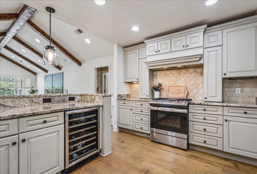 Gourmet kitchen featuring light-toned cabinetry, a built-in wine refrigerator, and stainless steel appliances