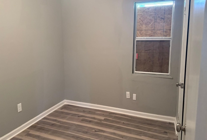 Room featuring wood-finish flooring, light gray wall paint, and white baseboards