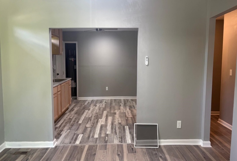 Open concept interior with light wood-finish flooring throughout, featuring a kitchen entry with light wood cabinetry