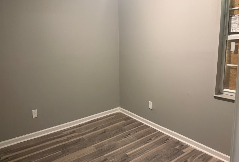 Interior room featuring neutral wall paint, wood-finish flooring, white baseboards, and a window with a sill