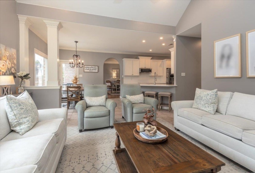 Inviting living area featuring a vaulted ceiling, neutral wall tones, and tile flooring