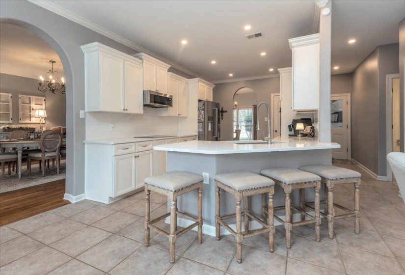 Spacious kitchen featuring white cabinetry, a large center island with a sink, stainless steel appliances, and tile flooring