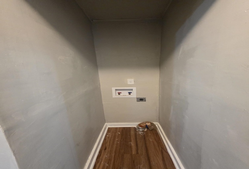 Dedicated laundry area featuring a wood-finish floor, white baseboards, and light gray walls