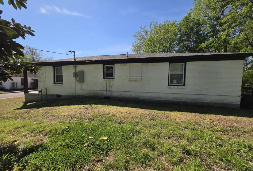 White brick exterior featuring dark trim, multiple windows, and a dark shingle roof