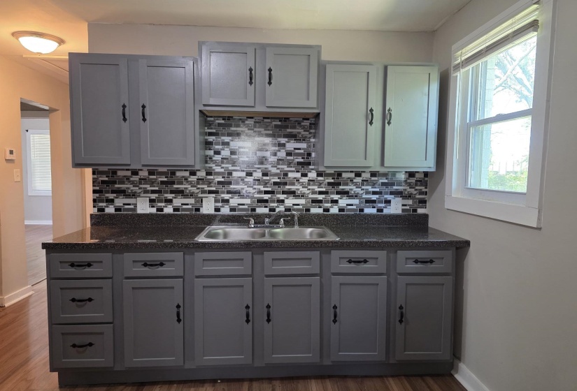 Kitchen featuring gray shaker-style cabinetry, a dual basin stainless steel sink, and a multi-tone mosaic tile backsplash