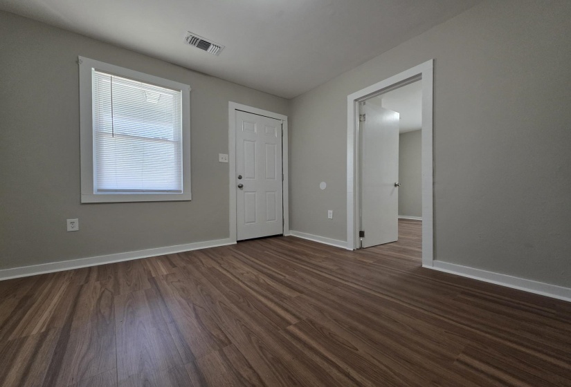 Room featuring wood-finish flooring, light gray wall paint, a white-framed window with blinds, and white trim throughout
