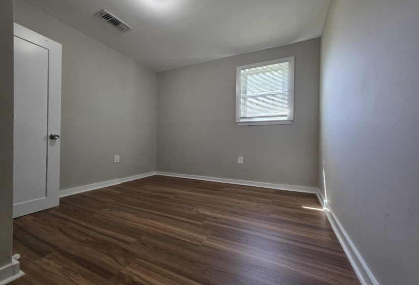 Room featuring wood-finish flooring, neutral wall tones, and white baseboards