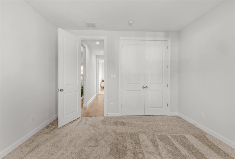 Neutral-toned bedroom featuring plush carpeting, a flat-panel interior door, and a double-door closet with polished hardware