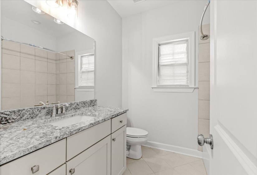 Bathroom featuring a dual-sink vanity with a speckled countertop, white cabinetry, and brushed nickel hardware