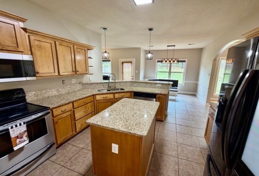 Kitchen featuring a central island, light wood cabinetry, and speckled countertops
