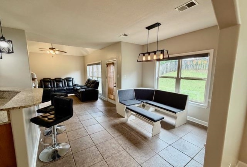 Tile flooring throughout main living areas, kitchen bar seating, picture window, recessed lighting, and a modern linear chandelier