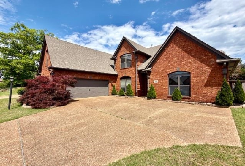 Brick exterior featuring a multi-gabled roofline, arched windows, and an attached garage with a dark gray door