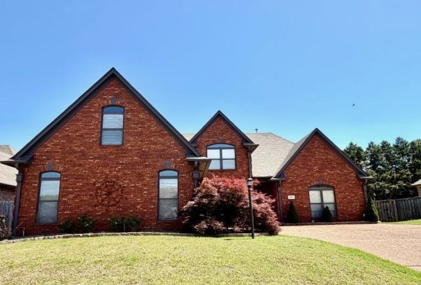Brick exterior with multiple gables, arched windows, and a paved driveway
